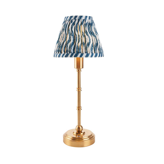 Ashstead LED table lamp with a slender brass stem, round base, and pleated blue, white, and gold ripple-patterned fabric shade, on a white background.