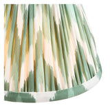 Close-up of the Ashstead LED Table Lamp's pleated zigzag shade in green, white and brass tones, showing the fabric pattern and warm glow.