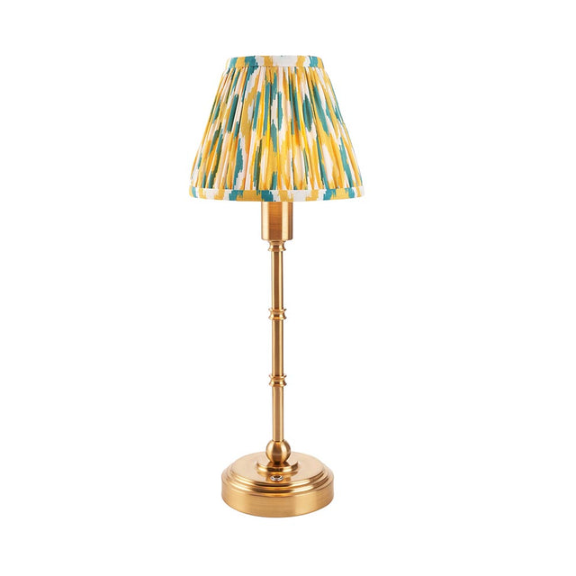 Ashstead LED table lamp with a slender brass stem and round base, topped with a pleated Ikat-print shade in yellow, teal and white, shown on a plain background.