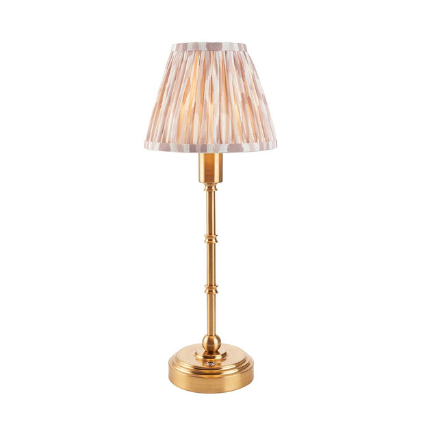 Endon Ashstead LED table lamp with brushed brass stem and pleated ikat-print fabric shade in white and natural tones, on a plain white background.