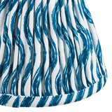 Close-up of the Ashstead LED Ripple Wall Light's pleated fabric shade, showing a blue wave print on white with brass trim detailing.