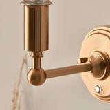 Close-up of Endon Ashstead LED wall light showing brushed aged brass arm, ball joint, cylindrical lamp holder and round wall plate.