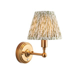 Endon Ashstead LED wall light with pleated green leaf-print faux linen shade on a brushed aged brass arm and round backplate, on white.