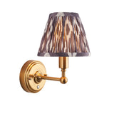 Ashstead LED Ikat wall light with a pleated grey, brown and white fabric shade on a brushed brass arm, shown against a white background.