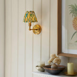Endon Ashstead LED wall light with brushed brass arm and tapered yellow, white and jade Ikat fabric shade, mounted on cream panelled wall beside framed print.