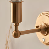 Close-up of the Endon Ashstead LED rechargeable wall light's brushed aged brass arm, ball joint, cylindrical lamp holder and circular wall plate.