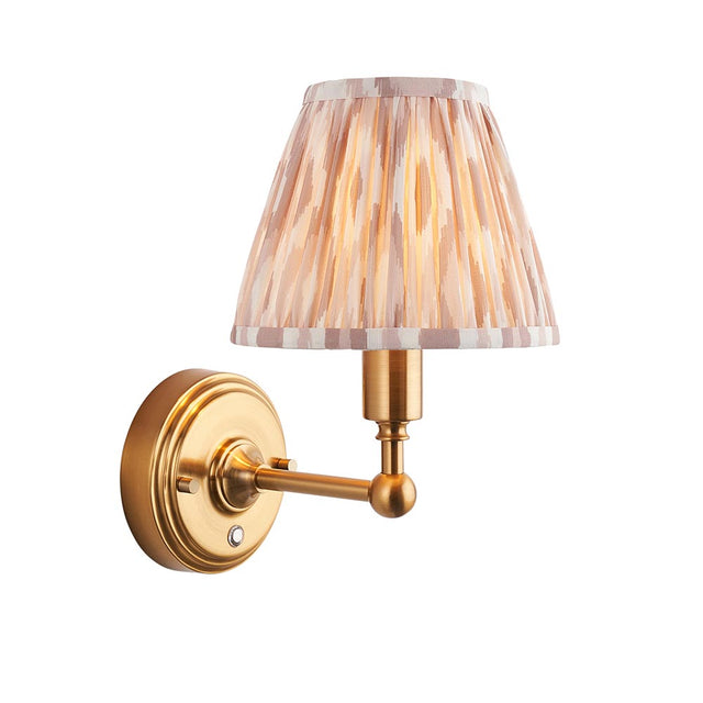 Endon Ashstead LED wall light with brushed brass arm and pleated Ikat shade in white and natural tones on a plain background.