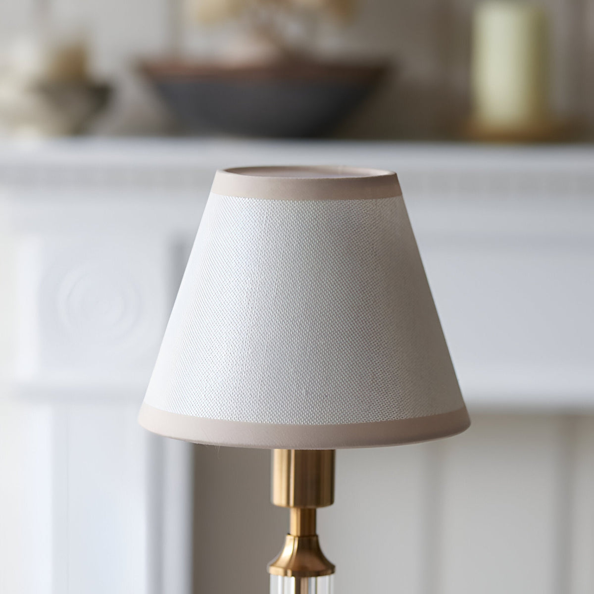 Endon Carlwood rechargeable table lamp with tapered vintage white fabric shade, almond taped edges and brushed brass base, on a mantel setting.