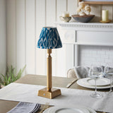 Cranwick LED Ikat rechargeable table lamp with brass reeded stem, square base and blue-white patterned shade, shown on a dining table.