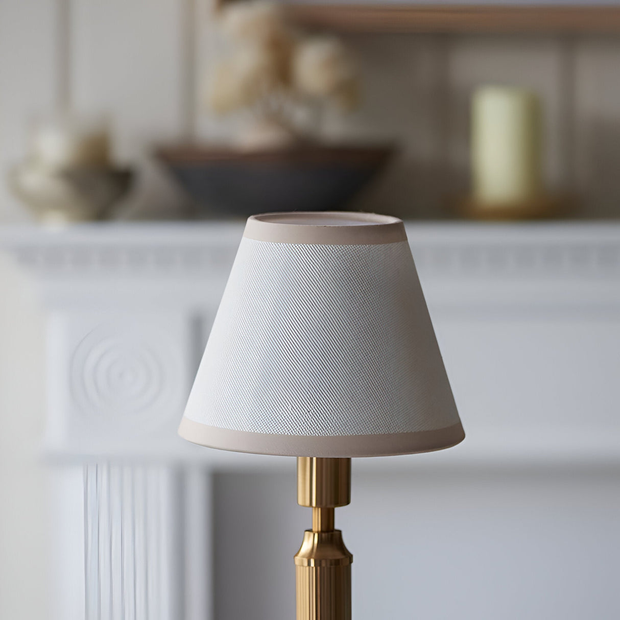 Endon Cranwick rechargeable table lamp with tapered vintage white Ivy fabric shade and reeded brushed brass stem on a mantel setting.