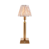 Cranwick LED Ikat table lamp with reeded brass stem, square base, touch dimmer, and pleated ivory-striped fabric shade on a plain white background.