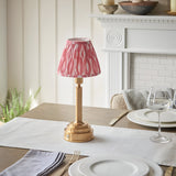 Endon Danebourne LED Ikat table lamp with brushed brass stepped base and pink and white pleated shade on a set dining table.