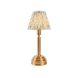 Endon Danebourne LED Leaf table lamp with brushed brass stepped base and tapered pleated shade in green and white leaf print, on a white background.