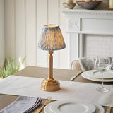 Danebourne LED Leaf Table Lamp in brass with pleated blue and white leaf-print shade, styled on a dining table beside a white fireplace mantel.