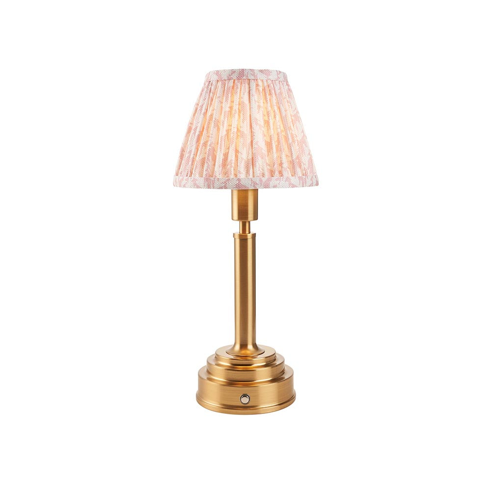 Danebourne LED Leaf table lamp with brass stepped base, cylindrical column, and pleated leaf-print fabric shade in pink and cream on a white background.