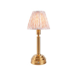 Danebourne LED Leaf table lamp with brass stepped base, cylindrical column, and pleated leaf-print fabric shade in pink and cream on a white background.