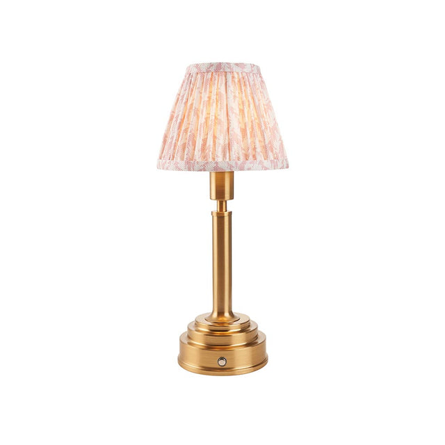 Danebourne LED Leaf table lamp with brass stepped base, cylindrical column, and pleated leaf-print fabric shade in pink and cream on a white background.