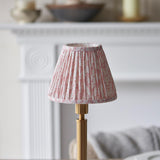 Danebourne LED Leaf Table Lamp with pleated pink patterned fabric shade on a stepped brass base, shown on a mantelpiece in a living room setting.