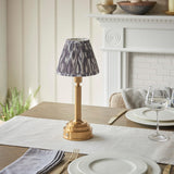 Endon Danebourne LED Ikat table lamp with brushed brass stepped base and grey and white pleated Ikat shade, on a dining table set with glassware.
