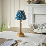 Danebourne LED Ikat Table Lamp with brass stepped base and blue-and-white patterned fabric shade, shown on a dining table near a white mantelpiece.