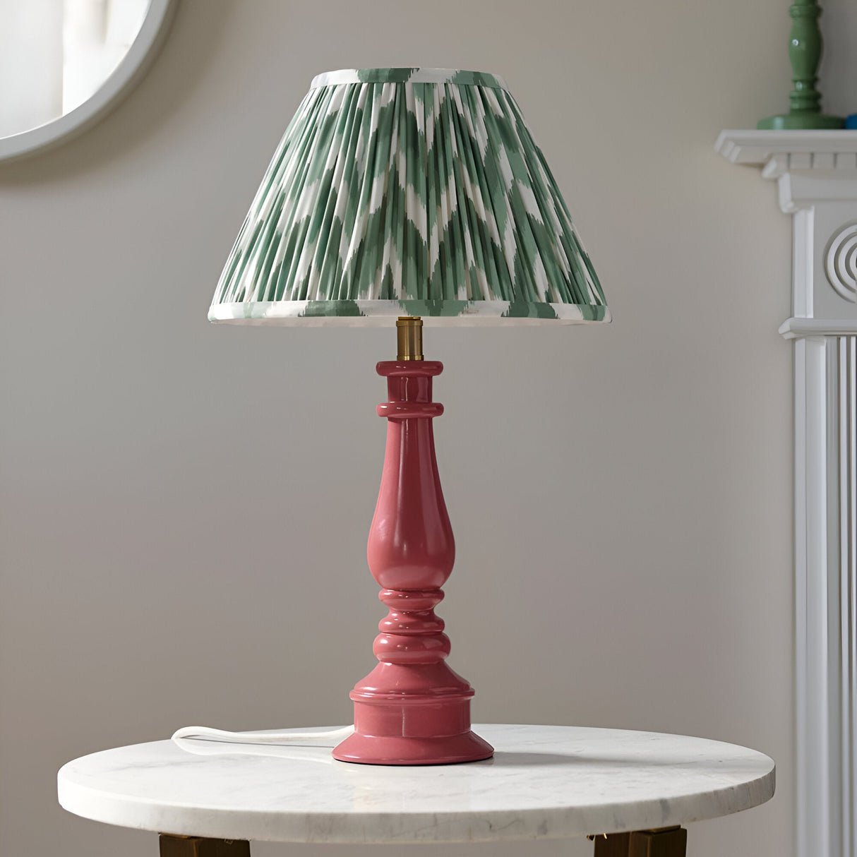 Endon Carlworth table lamp with turned pink resin spindle base and pleated green zigzag fabric shade, on a marble side table by a mirror.