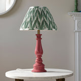Endon Carlworth table lamp with turned pink resin spindle base and pleated green zigzag fabric shade, on a marble side table by a mirror.