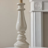 Close-up of the Carlworth table lamp's turned resin base in glossy almond white, showing spindle-style detailing and a brass B22 lamp holder.