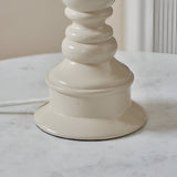 Close-up of the Carlworth Ikat Table Lamp's turned resin base in high-gloss cream, showing spindle detailing and braided flex on a marble surface.