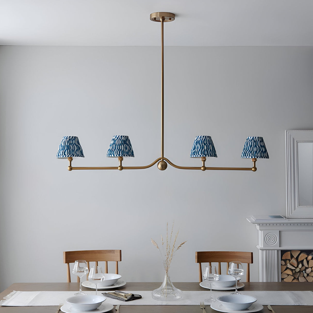 Cliffleigh 4 Light Ripple Pendant in brushed aged brass with blue patterned fabric shades, shown above a dining table in a light grey room.