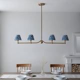 Cliffleigh 4 Light Ripple Pendant in brushed aged brass with blue patterned fabric shades, shown above a dining table in a light grey room.