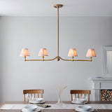 Cliffleigh Leaf 4 Light Linear Pendant in brushed brass with four pleated fabric shades on a slim bar, shown above a dining table in a light-toned room.