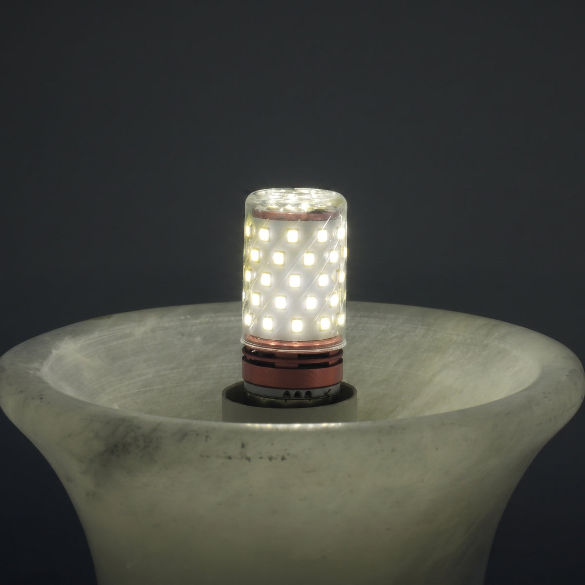 Close-up of the Morfia mushroom-shaped alabaster table lamp base with an illuminated LED corn bulb inserted, shown against a dark background.