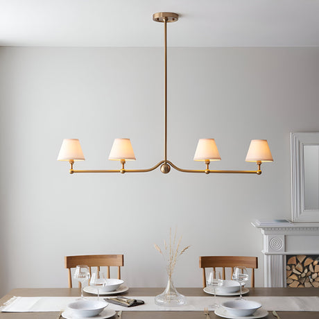 Endon Cliffleigh 4 light linear pendant in brushed aged brass with white tapered fabric shades, shown above a dining table near a fireplace.