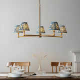Cliffleigh 5 Light Ripple Pendant in Blue, brushed aged brass frame with five tapered blue patterned fabric shades, shown above a dining table.