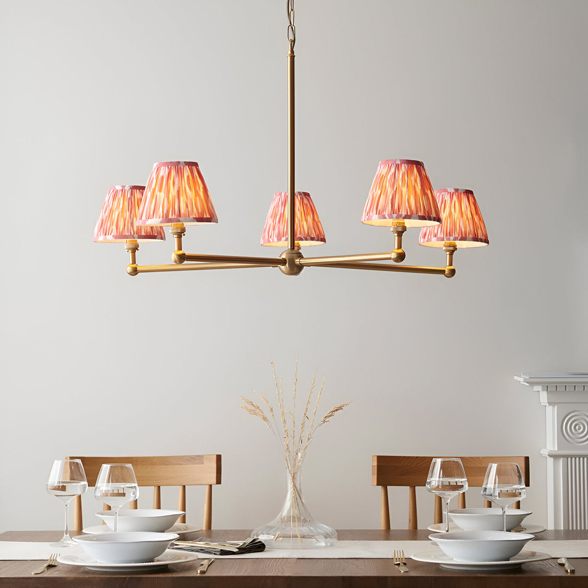 Endon Cliffleigh Ikat 5 light pendant in brushed brass with pleated pink Ikat tapered shades, shown above a wooden dining table setting.