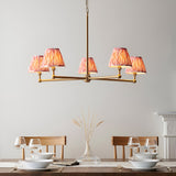 Endon Cliffleigh Ikat 5 light pendant in brushed brass with pleated pink Ikat tapered shades, shown above a wooden dining table setting.