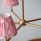 Close-up of the Endon Cliffleigh Ikat 5 Light Pendant showing the brushed brass central hub, radiating arms, and pleated coral pink Ikat shades.