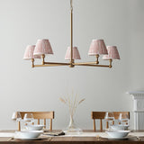 Cliffleigh Leaf 5 Light Pendant in brushed brass with five pleated pink Leaf-pattern shades, shown above a wooden dining table set with tableware.