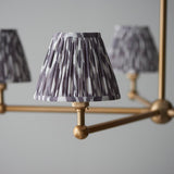 Cliffleigh Ikat 5 Light Pendant close-up showing brushed brass arms and ball joints with pleated grey Ikat-print fabric shades and taped edges.