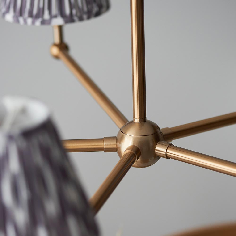 Close-up of the Cliffleigh Ikat 5 Light Pendant's brass hub and arms, with grey pleated Ikat-pattern shades against a plain light background.