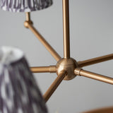 Close-up of the Cliffleigh Ikat 5 Light Pendant's brass hub and arms, with grey pleated Ikat-pattern shades against a plain light background.