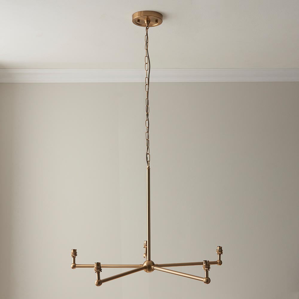 Cliffleigh Ikat 5-light pendant with brass finish, five candle-style arms on a central rod and chain, hanging in a neutral room without shades shown.