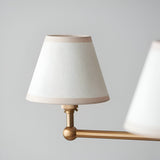 Close-up of an Endon Cliffleigh pendant shade in vintage white cotton mix with almond taped edges, mounted on a brushed aged brass arm.