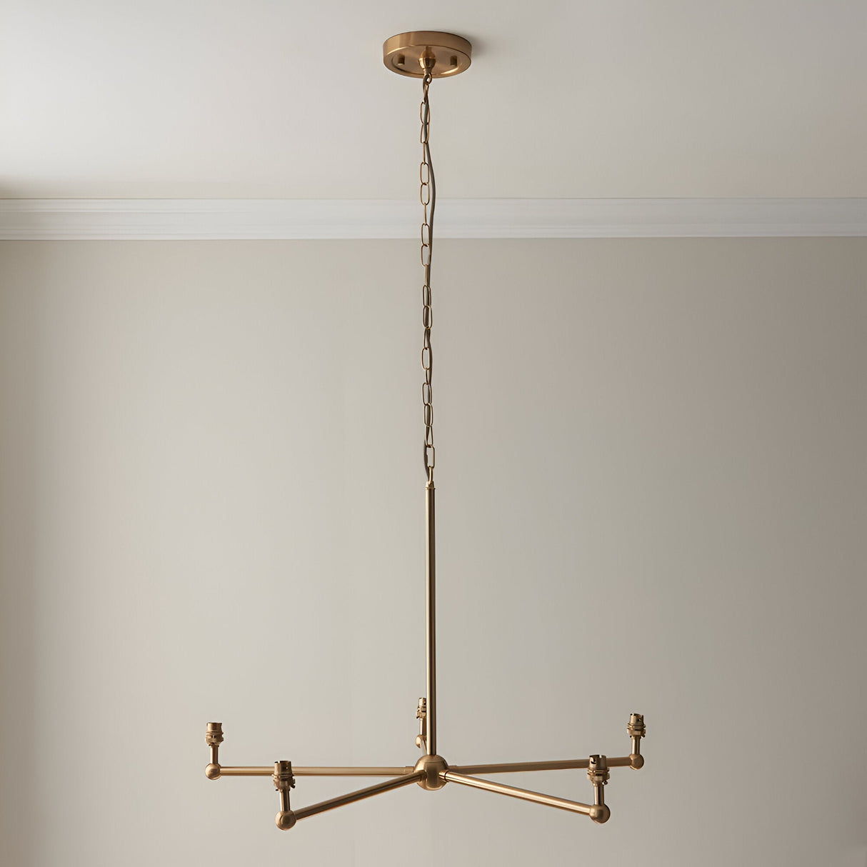 Endon Cliffleigh 5 light pendant frame in brushed aged brass, shown without shades on a chain suspension against a pale wall.