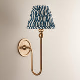 Endon Cliffleigh Ripple wall light in brushed aged brass with a pleated marlin blue faux linen tapered shade, mounted on a plain wall.