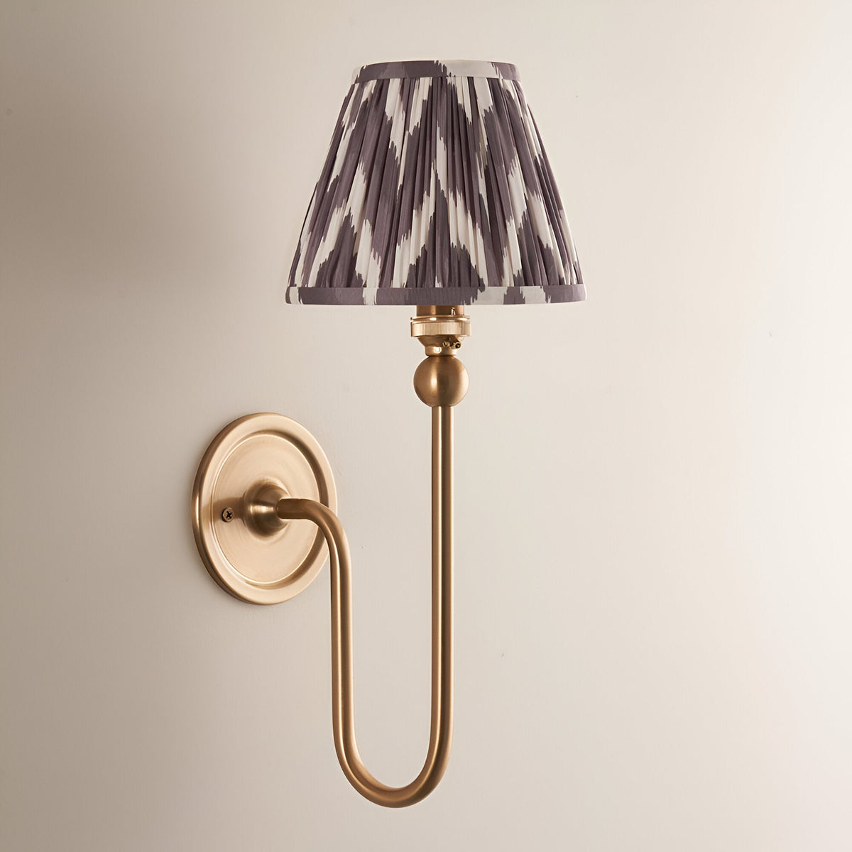Endon Cliffleigh Zigzag wall light in brushed aged brass with a slim curved arm and tapered pleated pearl grey zigzag faux silk shade.