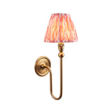 Endon Cliffleigh Ikat wall light in brushed brass with curved arm and pleated pink Ikat-print faux silk tapered shade, on a white background.