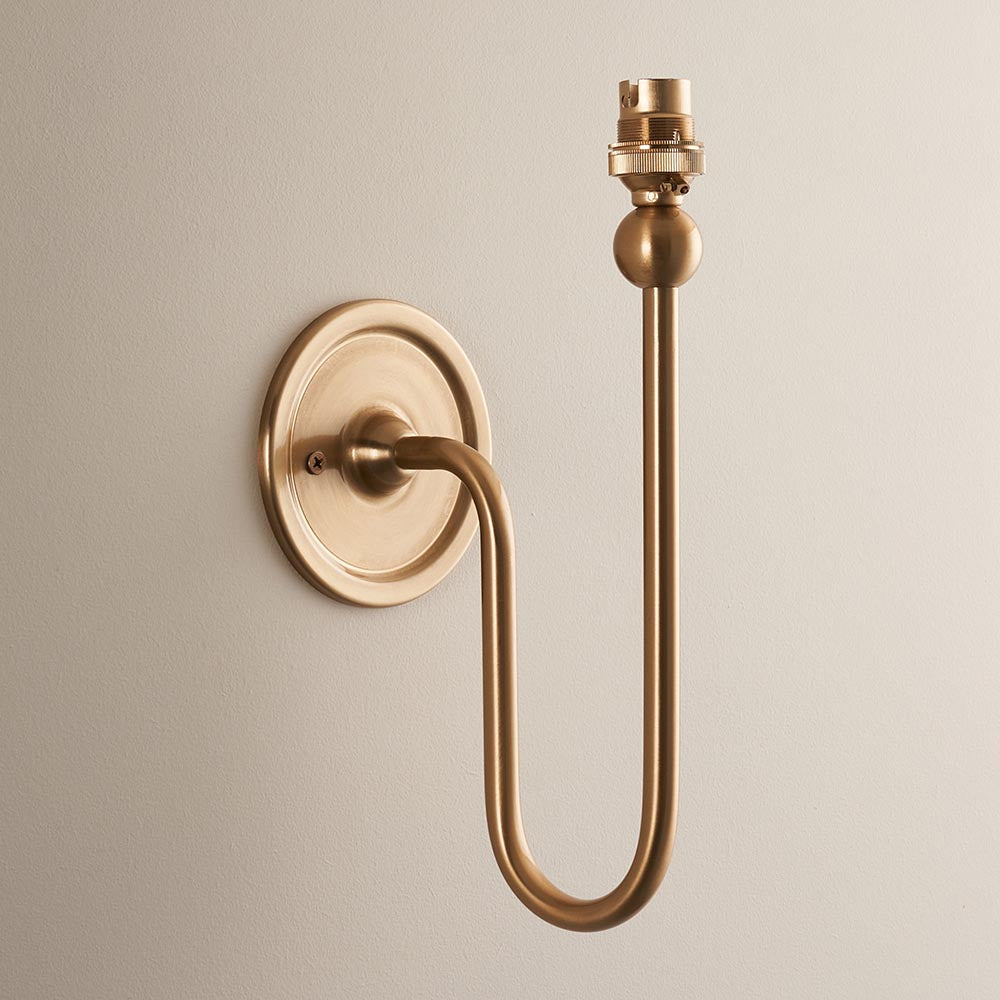 Endon Cliffleigh wall light fitting in brushed aged brass, with curved arm, flat round backplate and B22 lamp holder, shown on a neutral background.