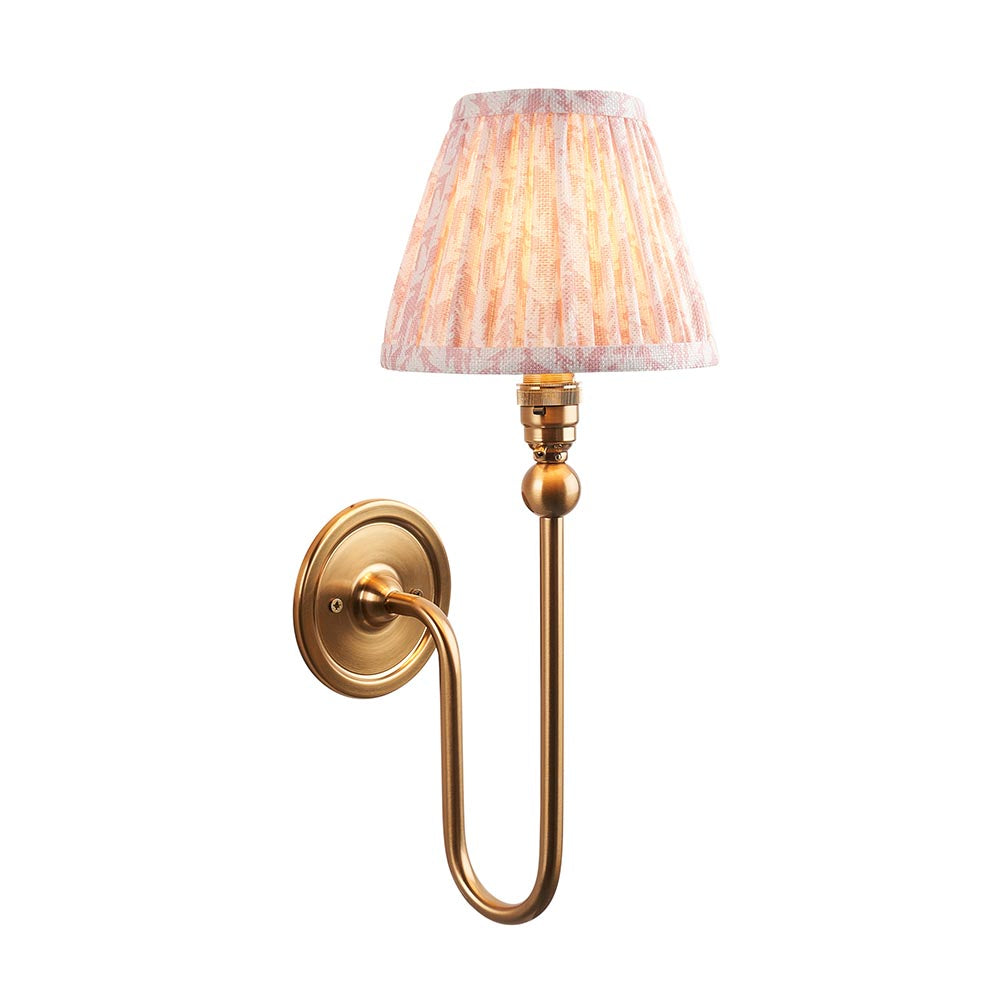 Endon Cliffleigh Leaf Wall Light II in brass with a curved arm and tapered pleated faux linen shade in peach leaf print, on a white background.