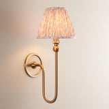 Endon Cliffleigh Leaf Wall Light II in brass, a curved single-arm wall light with a pleated peach leaf-print tapered fabric shade on a neutral wall.